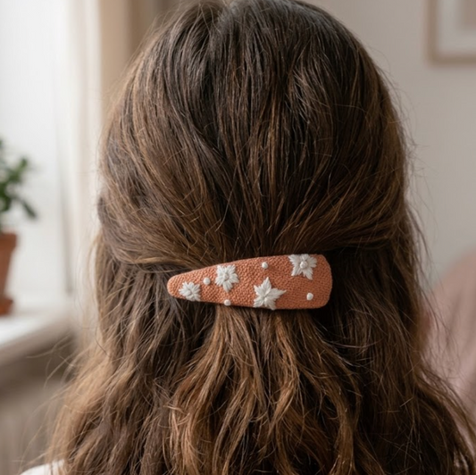Person with a decorative hair clip in their hair, with a window and plant in the background
