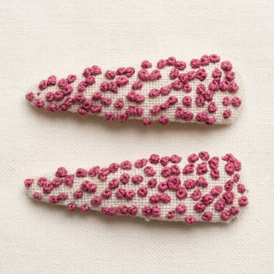 Two decorative hair clips with pink bead patterns on a light background