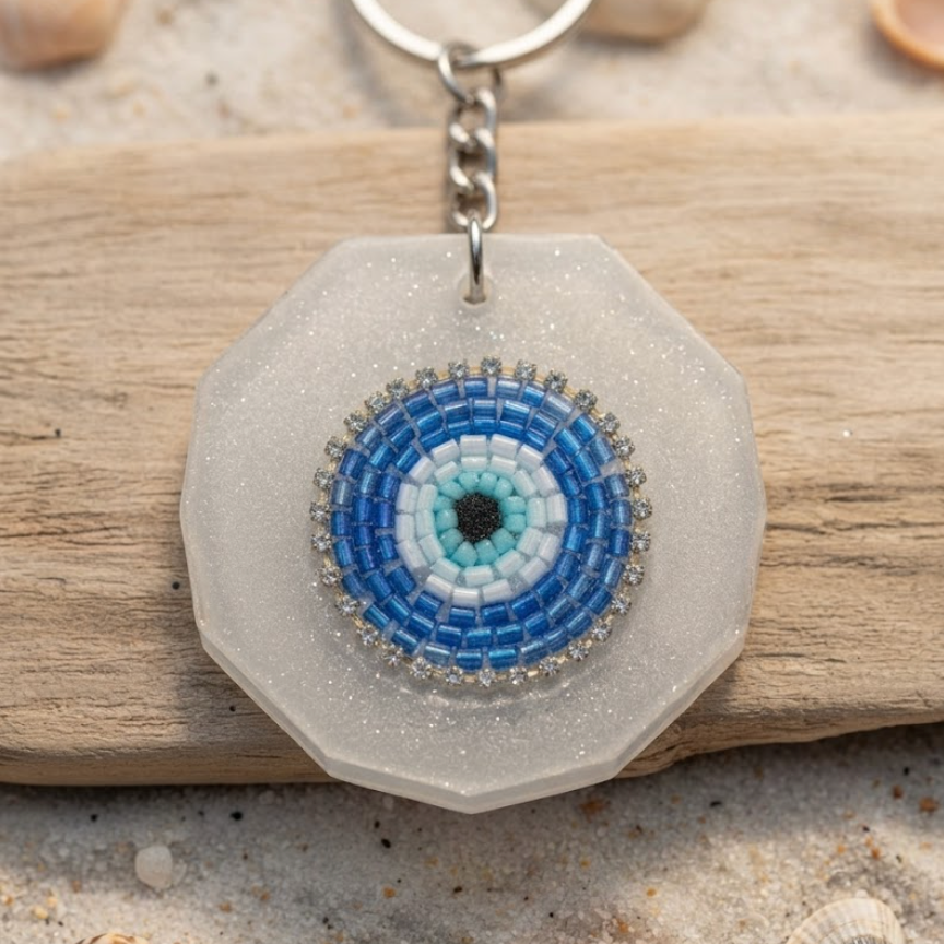 Hexagonal keychain with a blue and white circular design on a sandy background