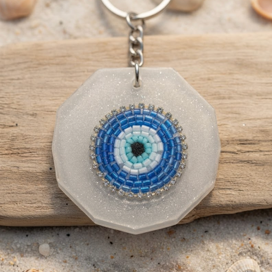 Hexagonal keychain with a blue and white circular design on a sandy background