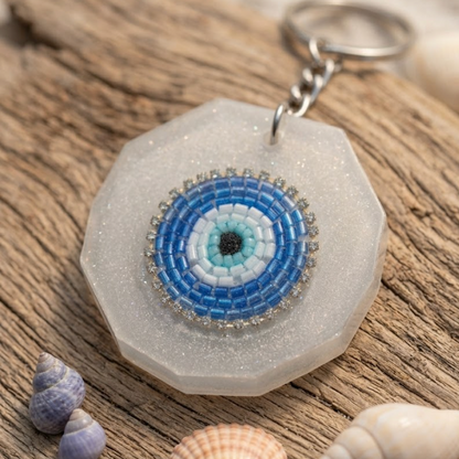 Hexagonal keychain with a blue and white circular design on a wooden surface with shells.