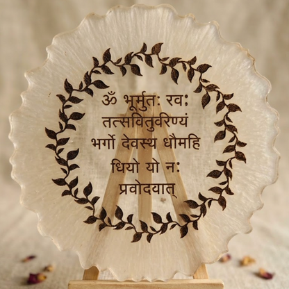 Decorative plate with engraved text and leaf design on a wooden stand.
