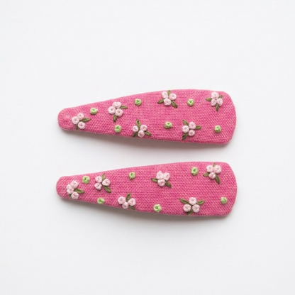 Pink hair accessories with pearls, makeup brush, and lavender on a textured surface